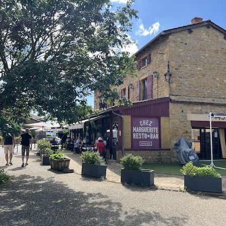 L'arrivée au village d'Oingt, classé plus beau village de France Vue sur le village d'Oingt en pierre dorée, végétation alentours et restaurant
