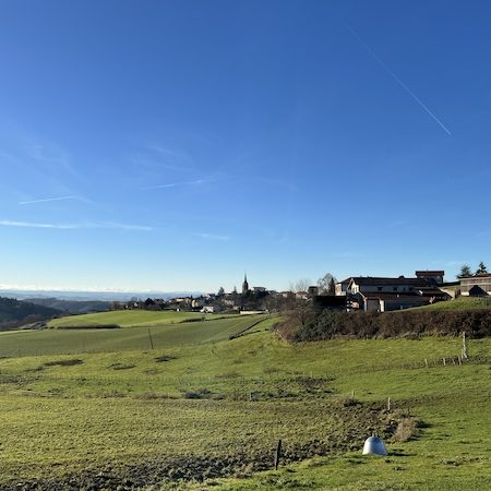 Le village de Maringes se détache sur les collines en herbes Panorama du village de Maringes dans les Monts du Lyonnais entouré de prés verdoyants