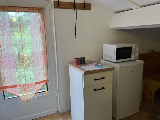 Placard bas avec frigo et micro-ondes, porte donnant sur le jardinet extérieur 