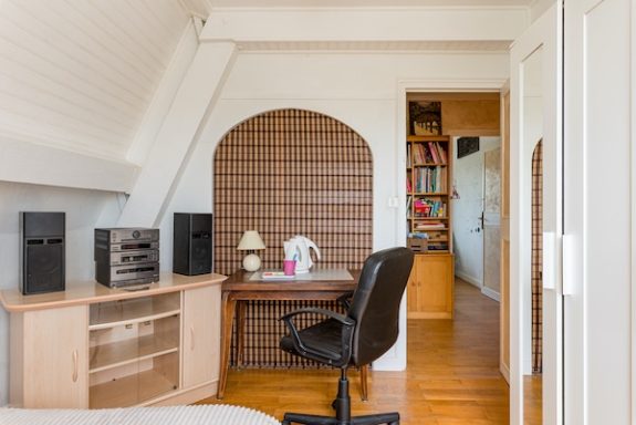 Coin détente de la chambre Fleur avec table et meuble de rangement bas, porte ouverte sur le couloir qui distribue les autres chambres