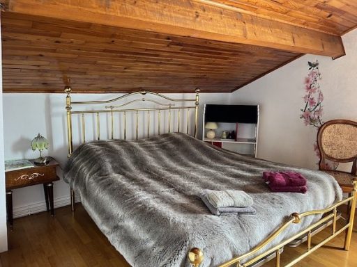 Chambre Iris - vue diagonale lit et chevets, lit laiton avec couvre-lit imitation fourrure de loup, chevets avec lampe, chaise en paille.