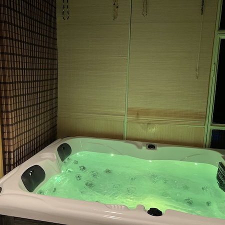 Séance spa en soirée dans la véranda avec lumière LED verte, avant le repas.