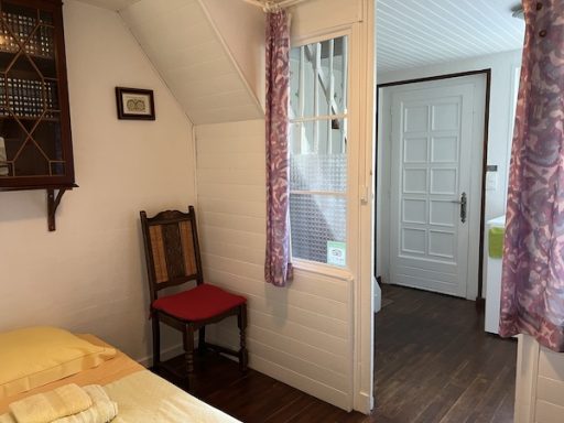 Vue sur un angle du lit de l'espace adolescent de la chambre Goélette et sa porte ouverte sur la cuisine et l'entrée.