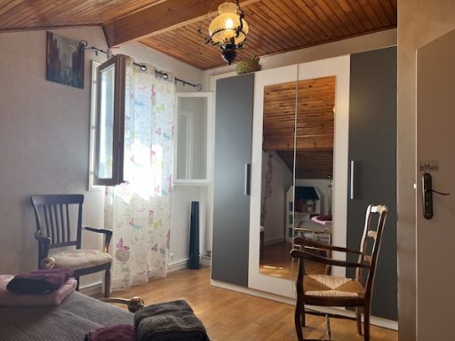 Chambre Iris - espace de vie avec armoire et 2 fauteuils, vue sur la fenêtre fermée avec un rideau