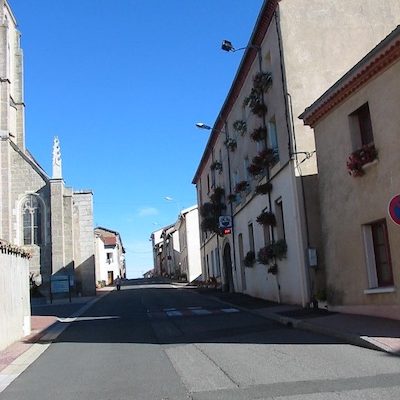 Rue principale montante du village de Maringes, église à gauche, mairie à droite