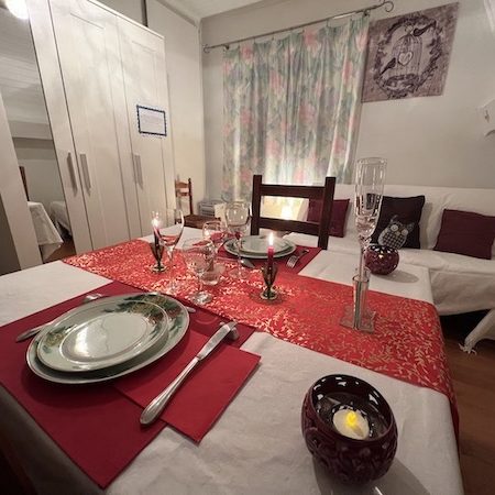 Promotion sur notre offre : massage et dîner en amoureux vue sur la table dressée nappe blanche assiettes vertes et bougies ambiance amoureux