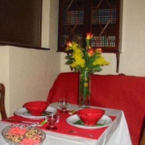 Table de petit déjeuner romantique Petit déjeuner romantique dressé avec bols rouges, fleurs et canapé rouge en arrière-plan