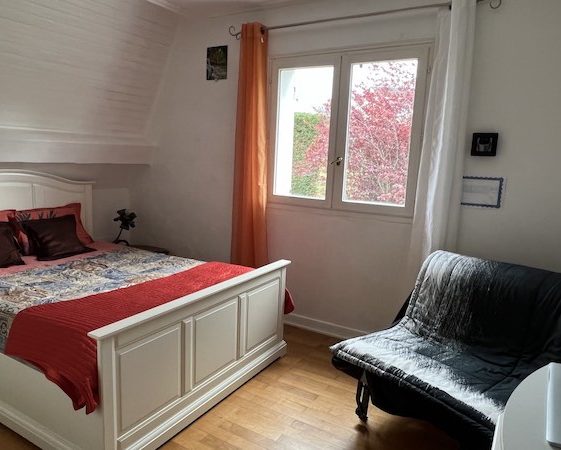 Chambre Perle avec lit double et 2 oreillers, fauteuil confortable, vue fenêtre qui donne sur cerisier à fleurs à f